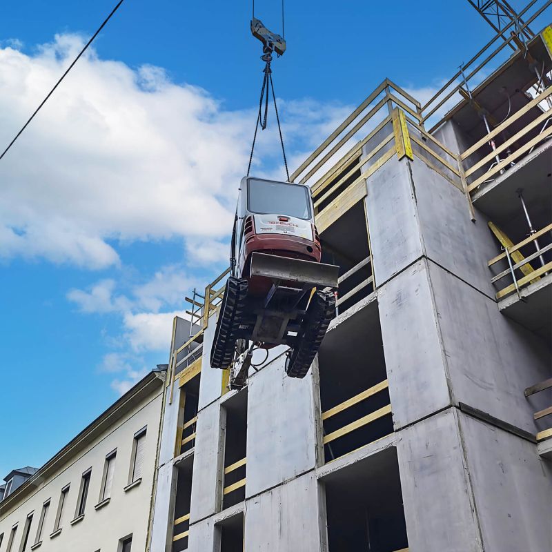 BMK Baumaschinen Services - Minibagger wird von einem Kran auf eine Baustelle gehoben, Ihr Experte für Baumaschinen in Wien und Niederösterreich